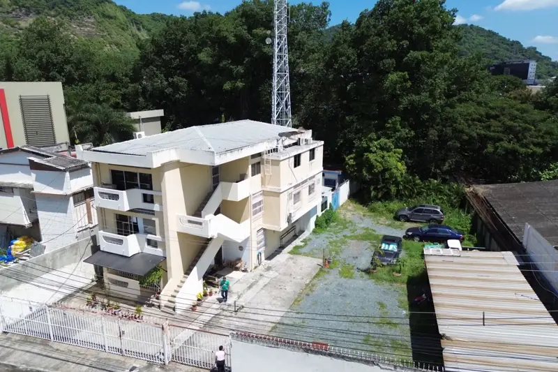 Toma aérea oblicua de una edificación de tres plantas con patio de estacionamiento
